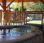 Centrally located hot tub under rustic log-beam covered area